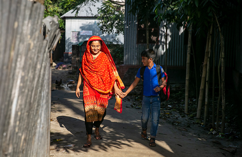 Samia, 17, walks with her younger brother near their home in Rajbari District, Bangladesh
